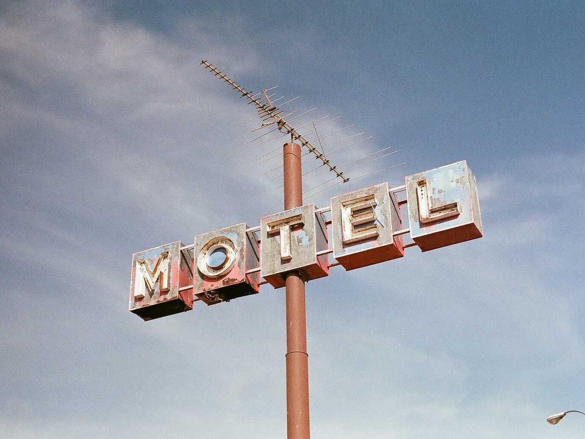 Vintage motel sign with antenna against a blue sky, evoking a sense of nostalgia and Americana.