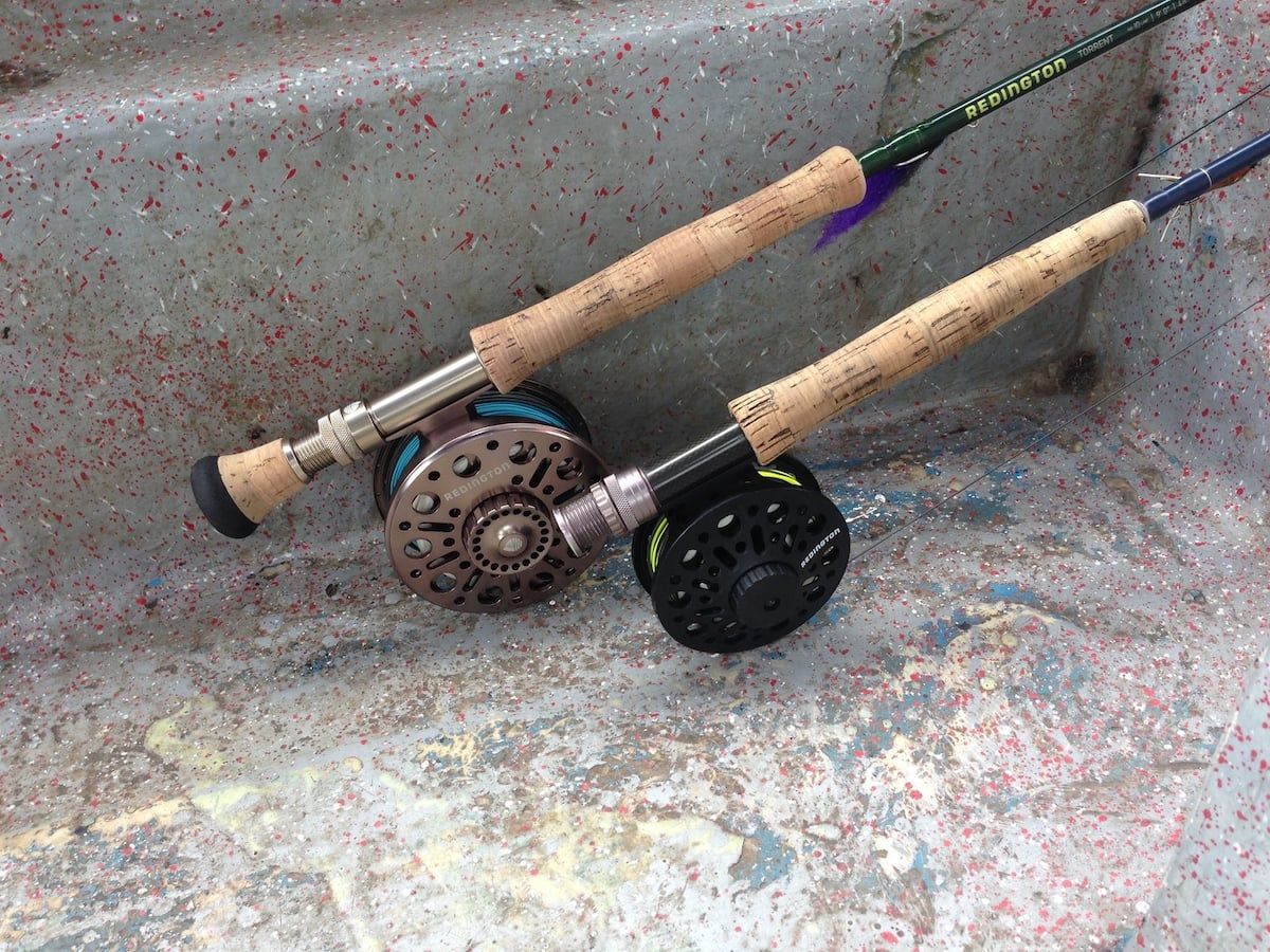 Two Redington fishing rods with reels resting on a speckled concrete surface, ready for a wildlife fishing adventure at Gatun Lake in Panama City.