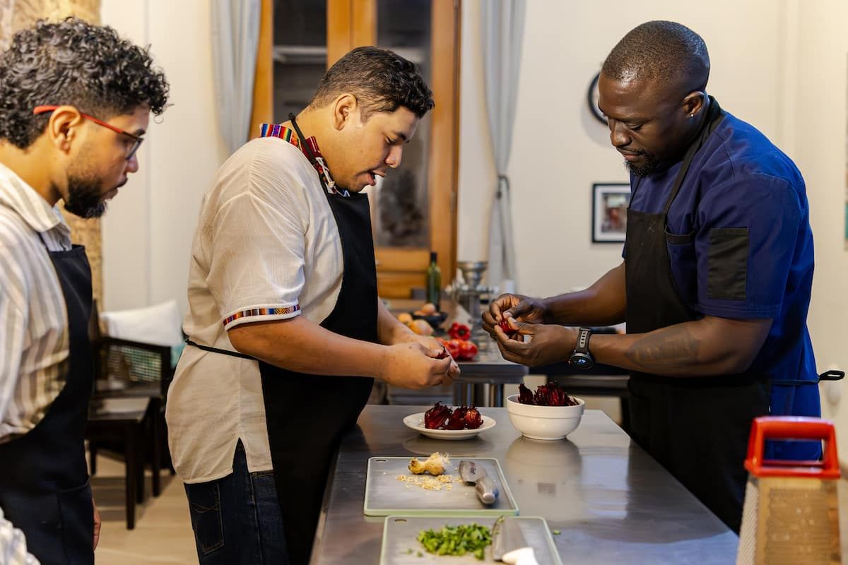 Trois chefs en tabliers préparant des ingrédients lors d'un cours de cuisine afro-panaméen à Casco Viejo, Panama.