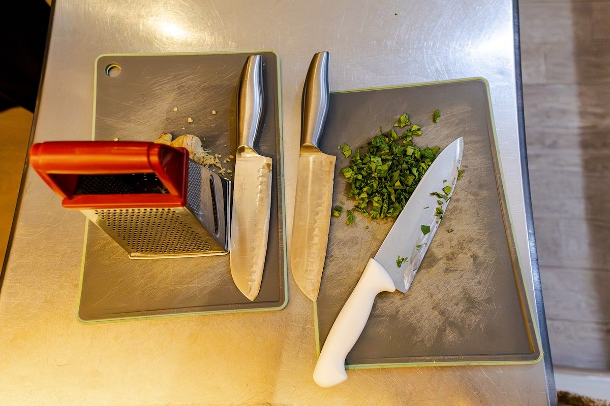 Outils de cuisine et herbes hachées sur des planches à découper lors d'un cours de cuisine afro-panaméen à Casco Viejo, Panama.