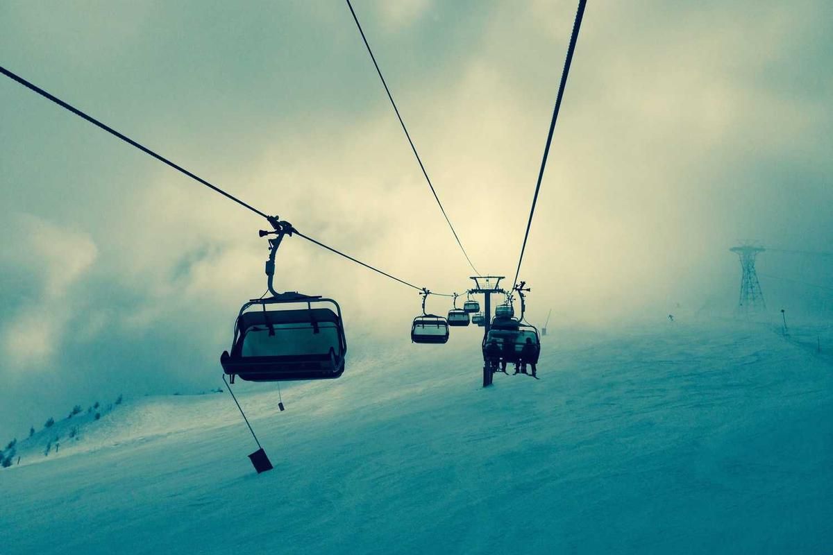 Ski lift ascending a snowy slope in a foggy mountain setting, evoking a serene winter atmosphere for outdoor adventure enthusiasts.