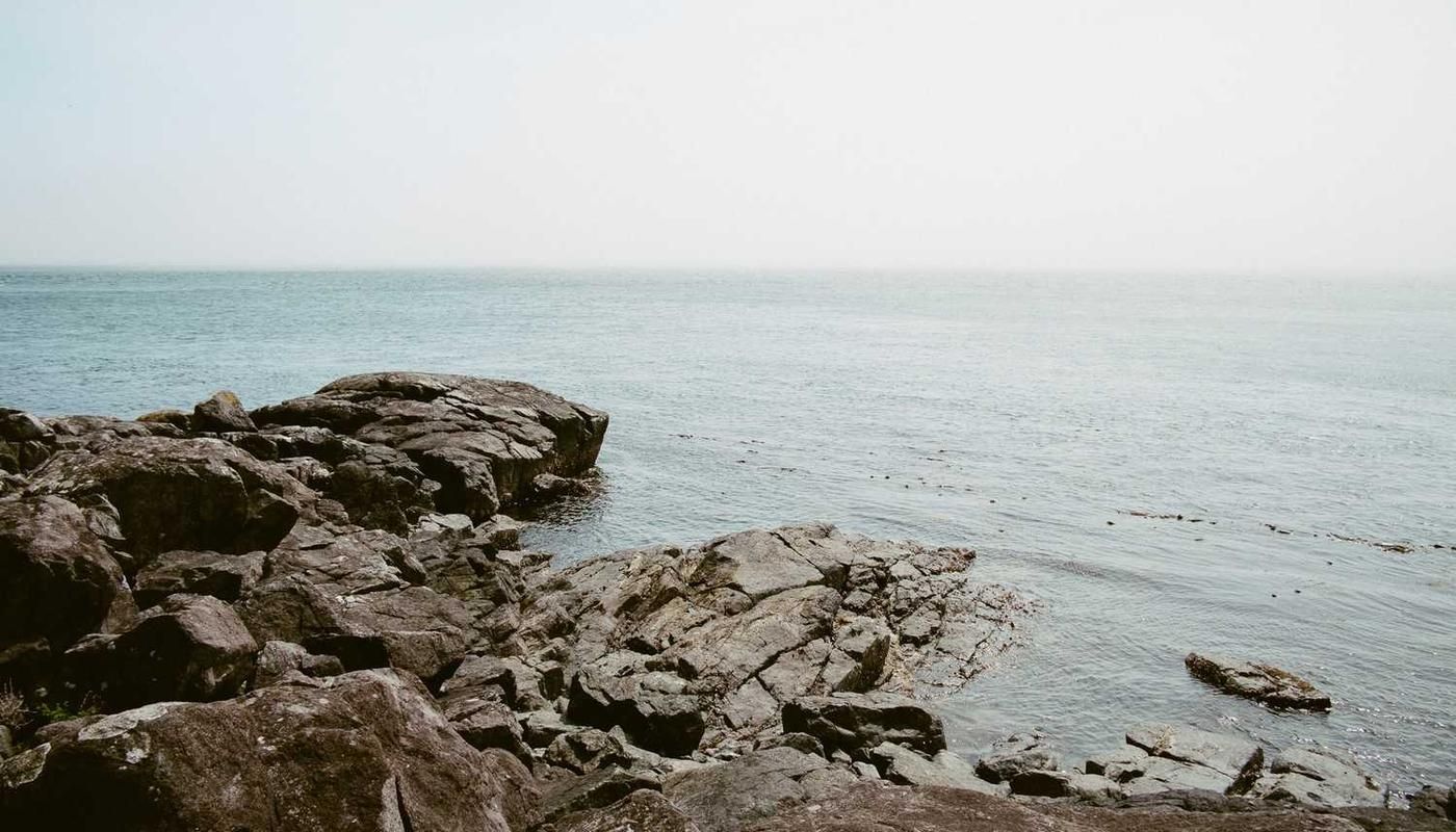 Côte rocheuse lors de la visite d'observation des oiseaux sur la Route Pipeline à Panama, avec des eaux océaniques calmes et un ciel brumeux, idéal pour observer la faune côtière.