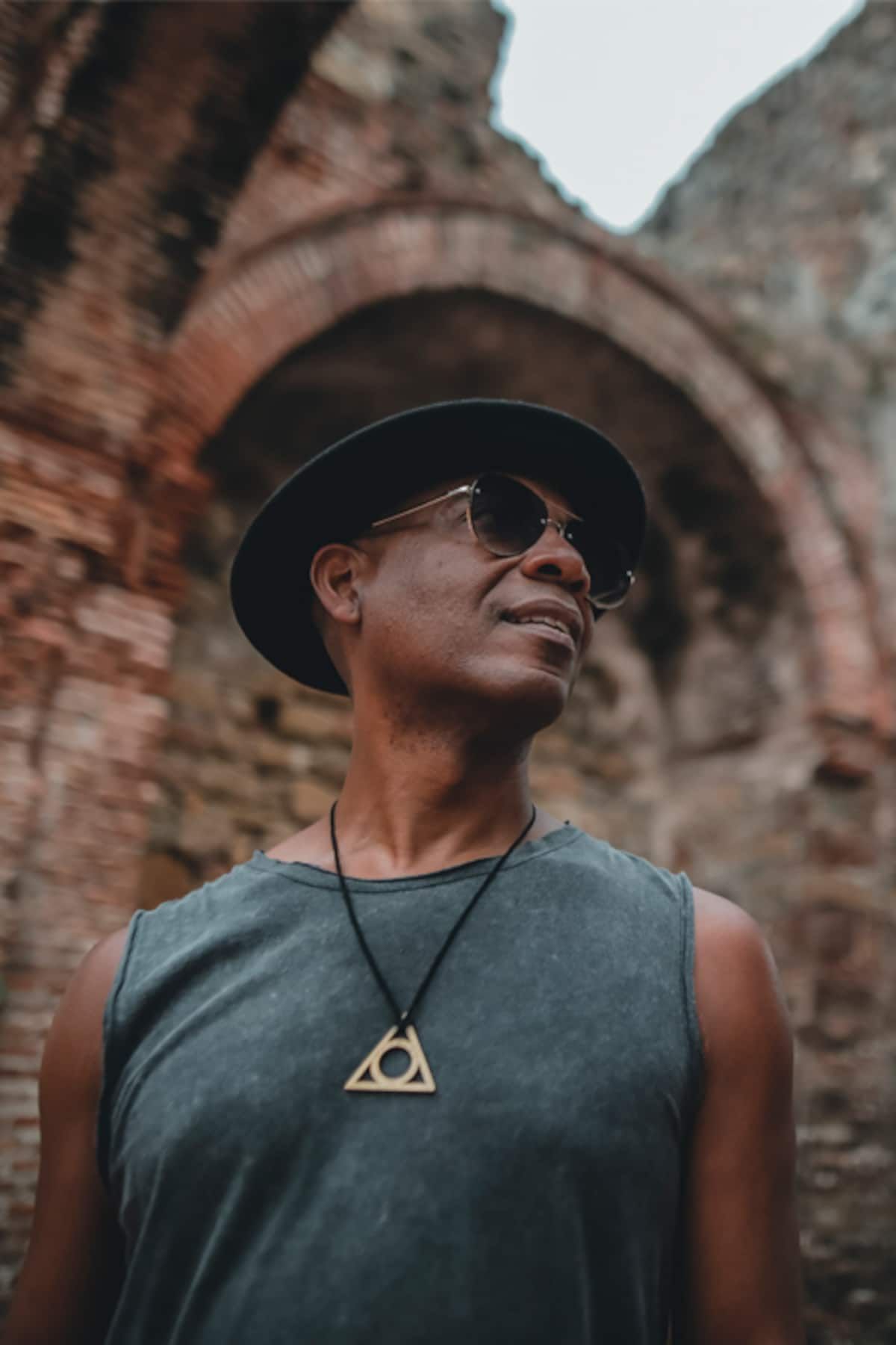 Man in a hat and sunglasses poses in front of an ancient brick archway during a photo walking tour in Casco Antiguo, Panama City.