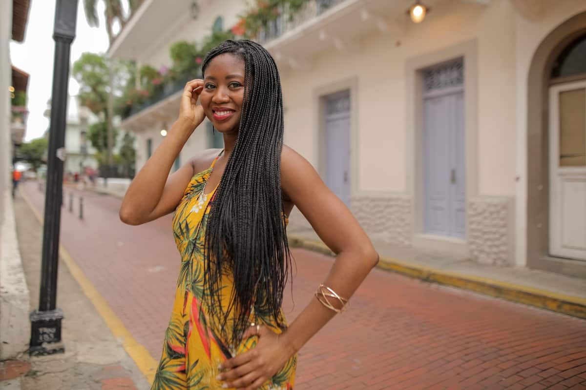 Woman in a yellow tropical dress poses on cobblestone streets during a photo walking tour in Casco Antiguo, Panama City.