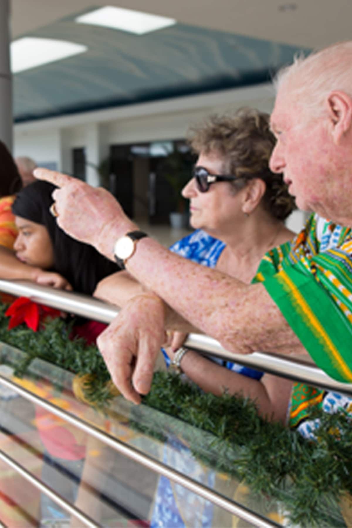Elderly man points while on a balcony with two women during a photo walking tour in Panama City, Panama