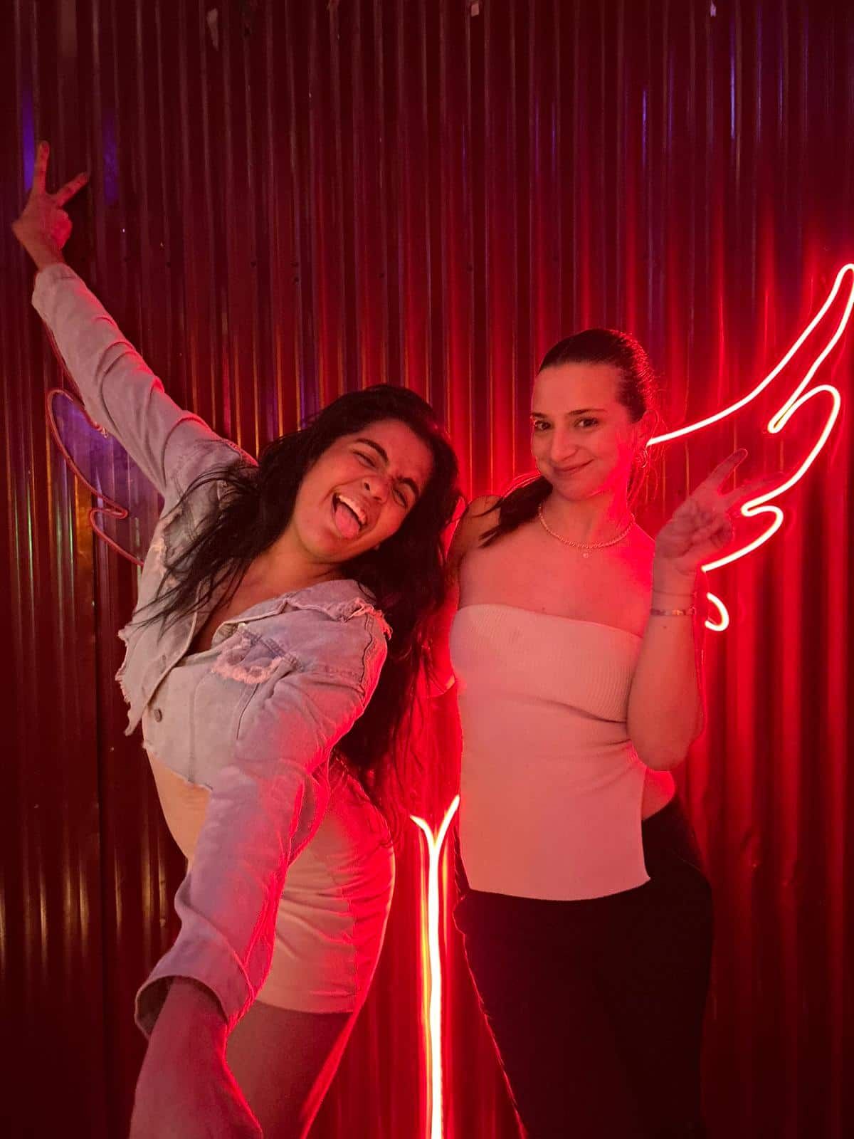 Two women posing with neon wings at a bar crawl in Casco Viejo, Panama City, enjoying the vibrant nightlife atmosphere.
