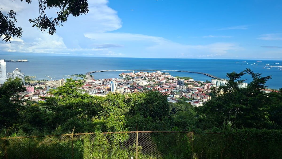 Panorama of Panama City from Cerro Ancon, featuring Mi Pueblito neighborhood, ocean view, and the Panama Canal under a sunny sky.