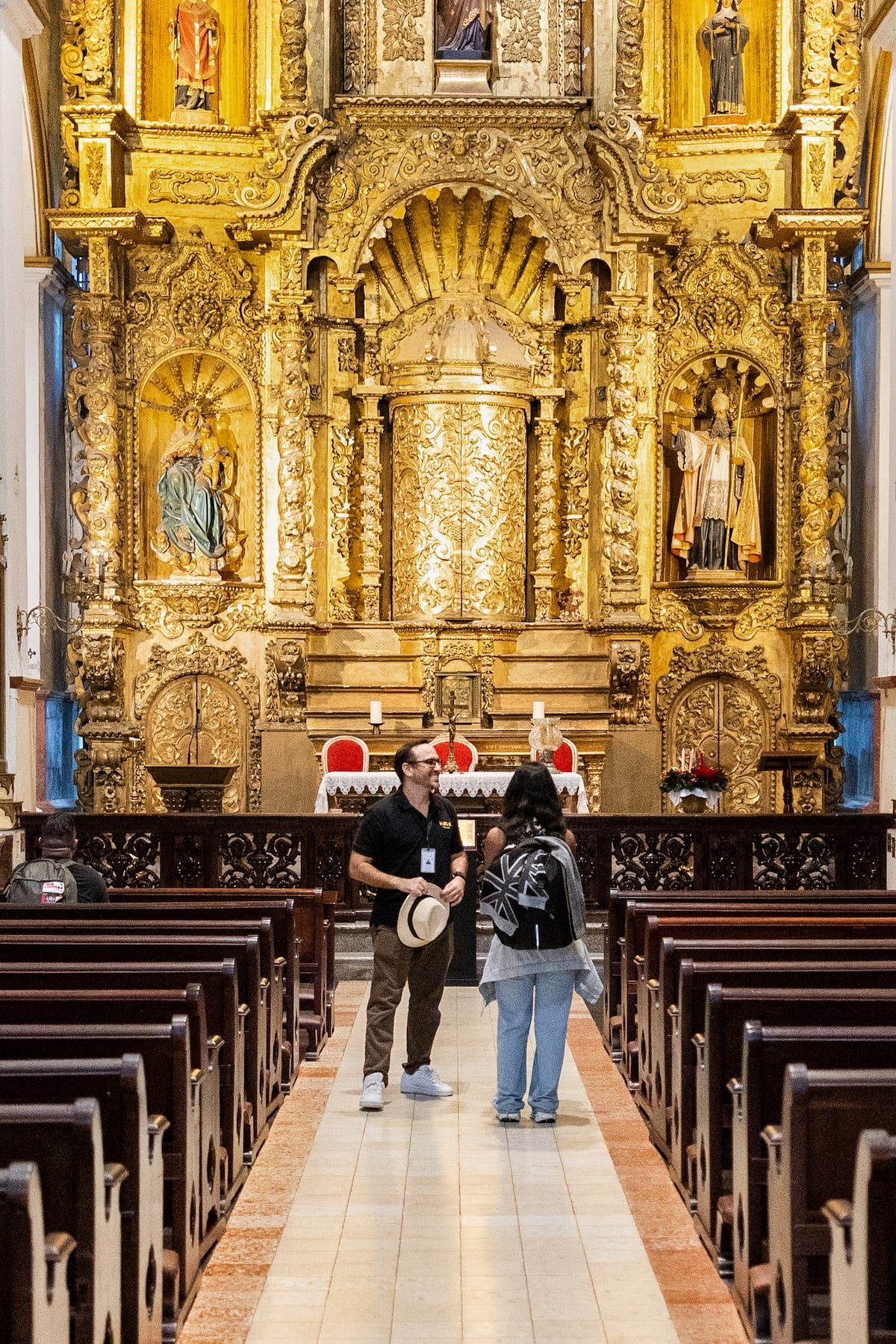 Tourists explore the ornate gold altar of a historic church during the Discover Casco Viejo Secrets Tour in Panama City, Panama.