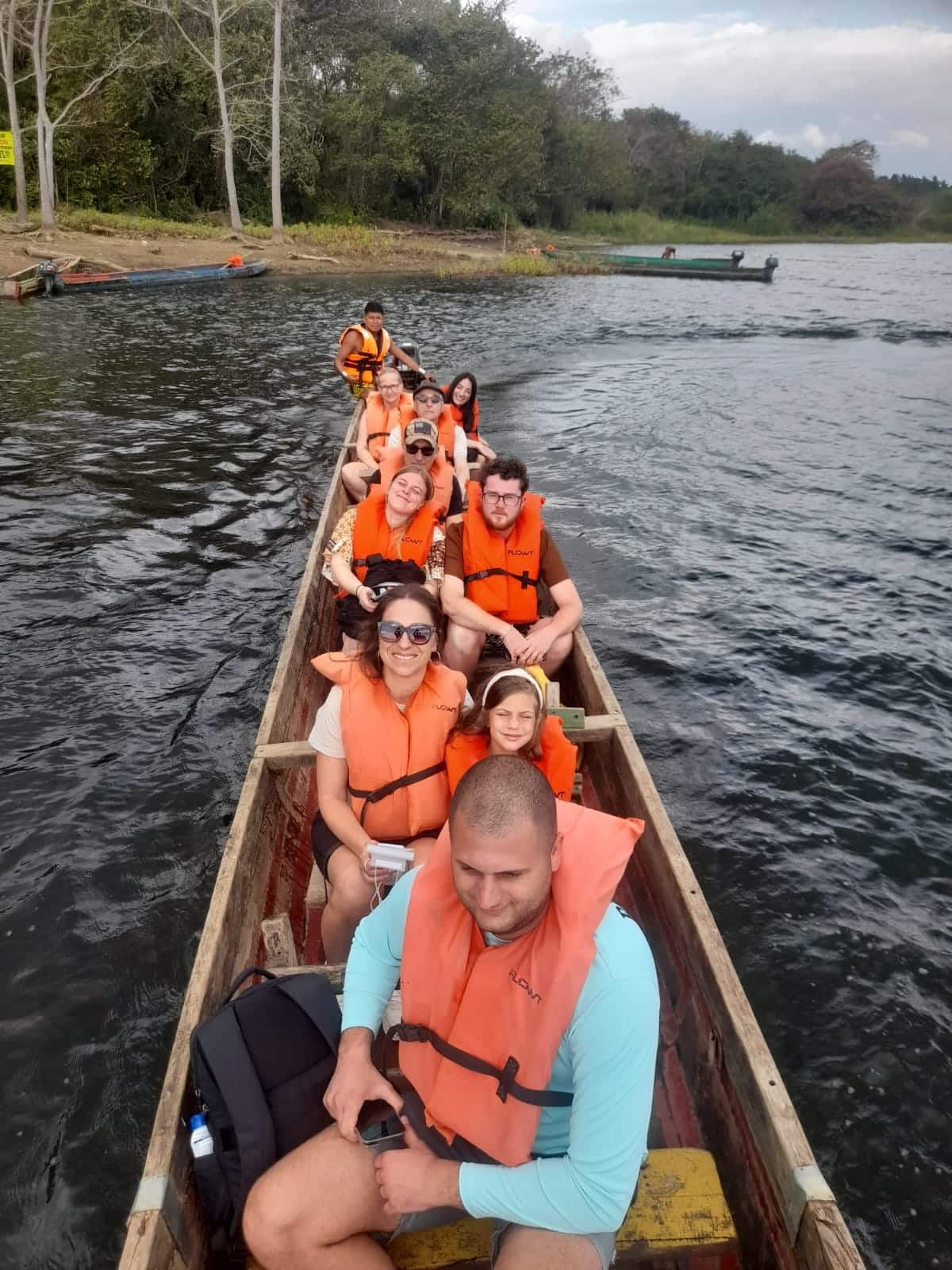 Des touristes portant des gilets de sauvetage orange profitent d'une balade en pirogue lors de la visite du village autochtone Embera à Panama, entourés de verdure luxuriante.