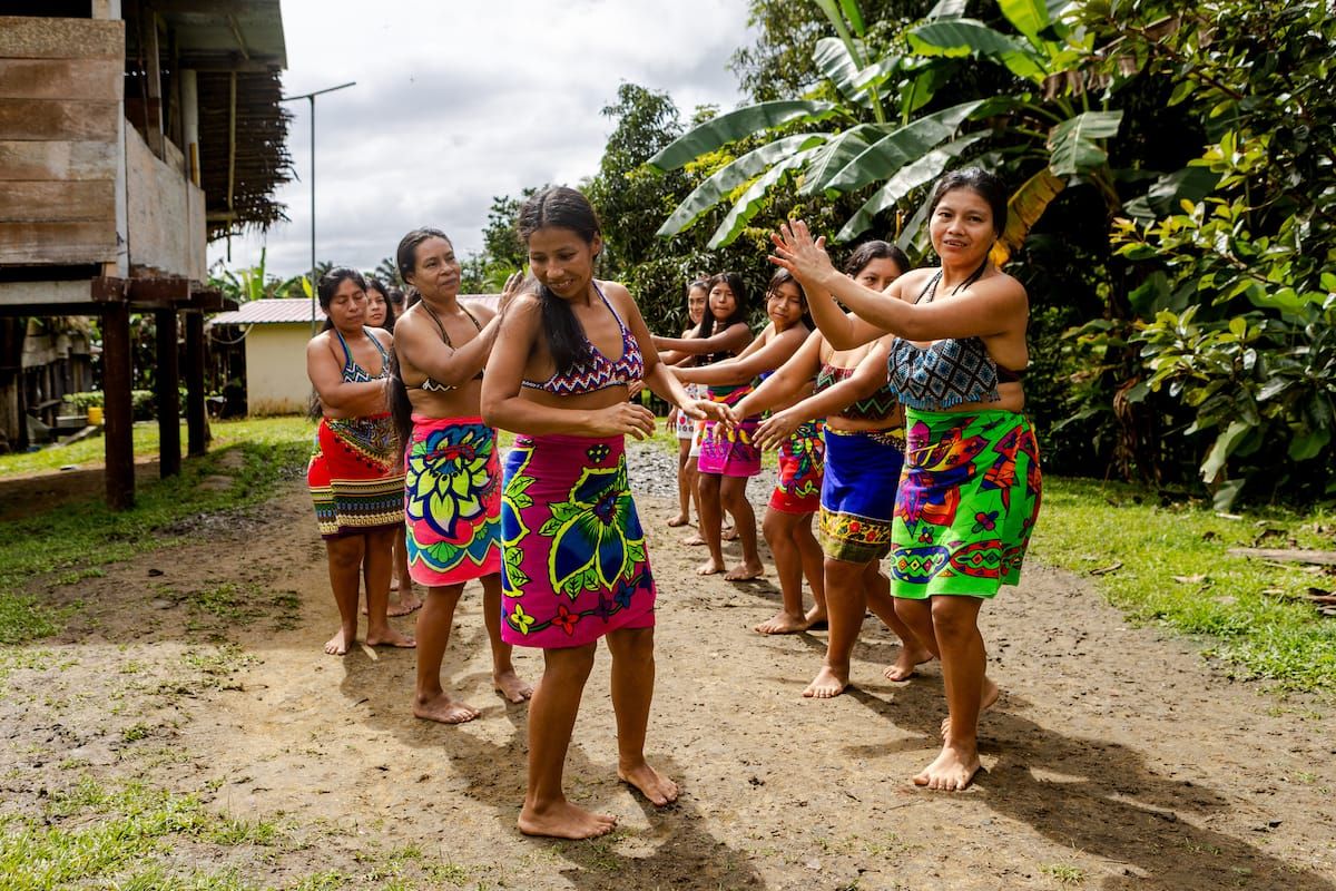 Femmes autochtones Embera exécutant une danse traditionnelle en tenues colorées dans un village rural au Panama.