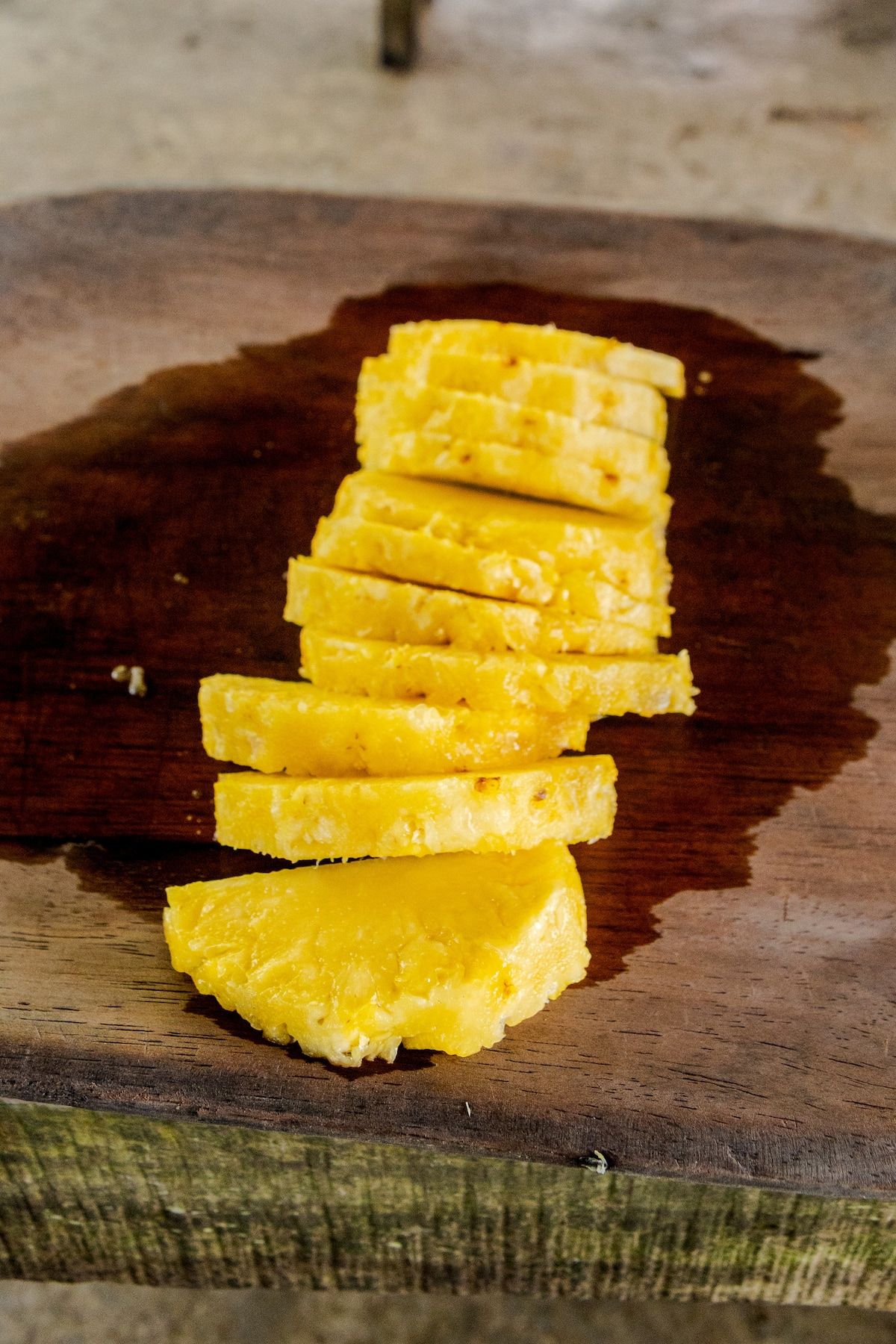 Stacked slices of fresh pineapple on a wooden cutting board, showcasing vibrant yellow color and juicy texture for the Embera Indigenous Village Tour in Panama.