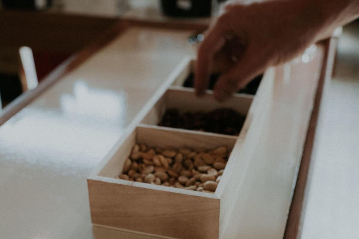 A hand selecting nuts from a wooden tray during a Geisha Coffee Chocolate Tasting experience in Panama City, highlighting the sensory journey of exploring local flavors.