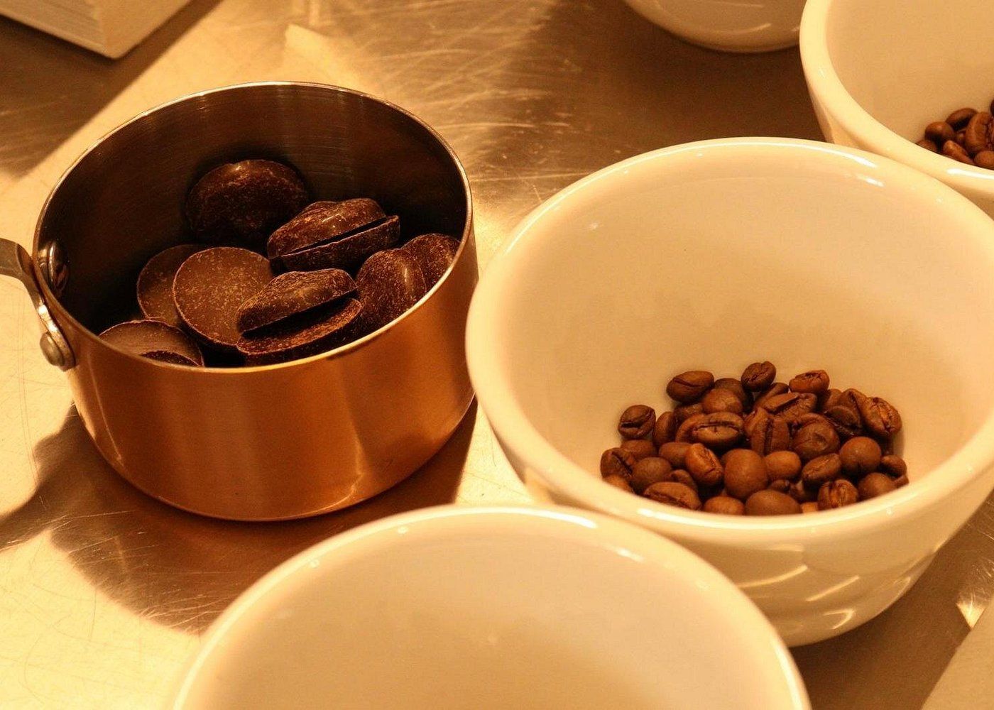 Geisha coffee beans and chocolate pieces arranged in bowls and a copper saucepan for a gourmet tasting experience in Panama City.