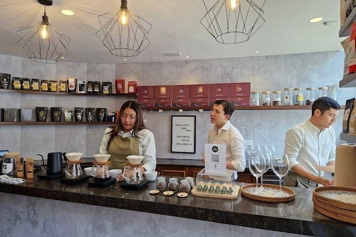 Barista preparing Geisha coffee using pour-over method at a modern café in Panama City, with customers observing the process.