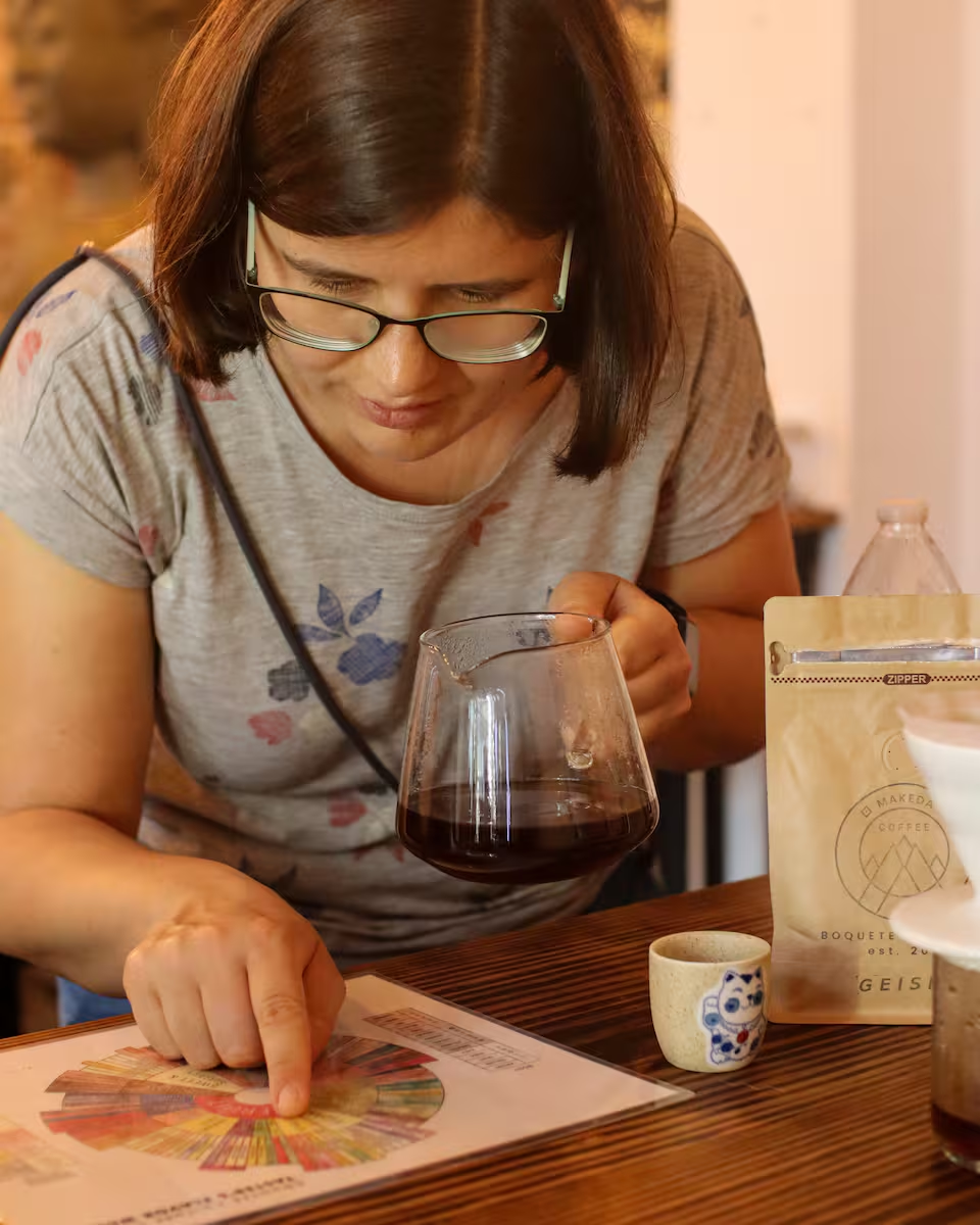 Woman tasting Geisha coffee at a café in Panama City, examining a color chart for flavor notes during an immersive coffee experience.