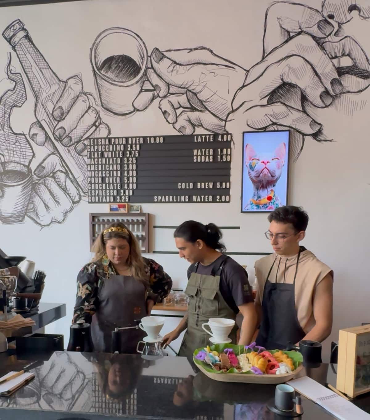 Baristas prepare Geisha coffee using a pour-over method at a café in Casco Viejo, Panama City, with a menu board and artistic mural in the background.
