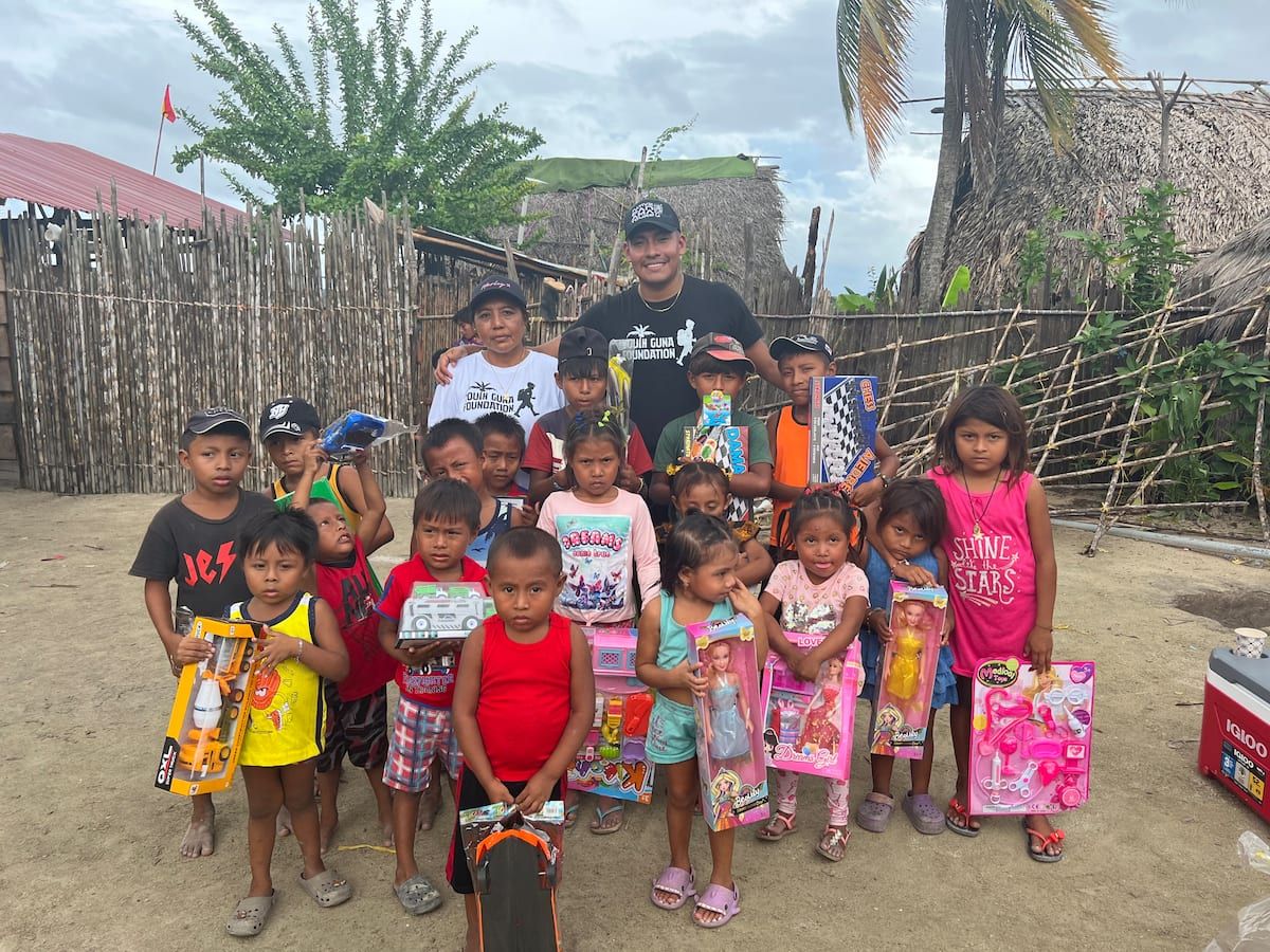 Children and adults gather in a rural village, holding new toys during a community outreach event as part of the Guna Culture Urban Tour in Casco Viejo, Panama.