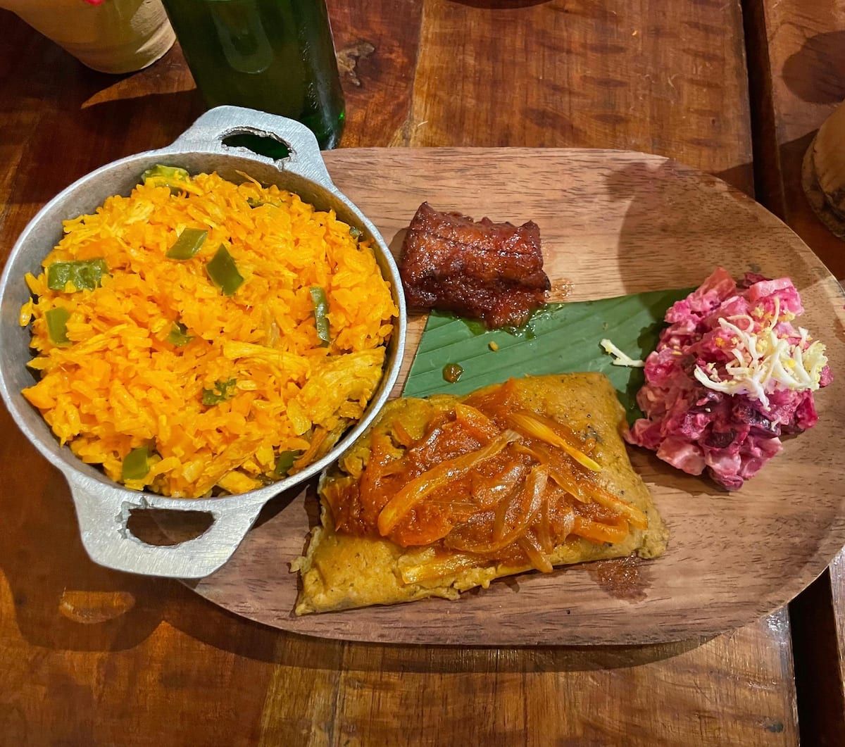 Traditional Panamanian meal with yellow rice, tamale, pickled cabbage, and meat served on a wooden plate at Bandits Adventure Tours Panama's Guna Culture Urban Tour in Casco Viejo.