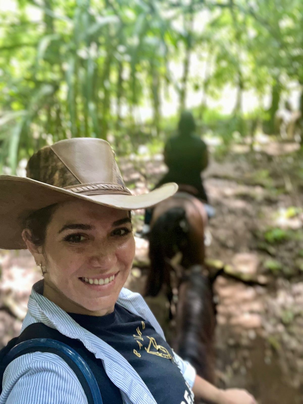Woman smiling during a horseback riding adventure through a lush forest trail in Panama City, Panama.
