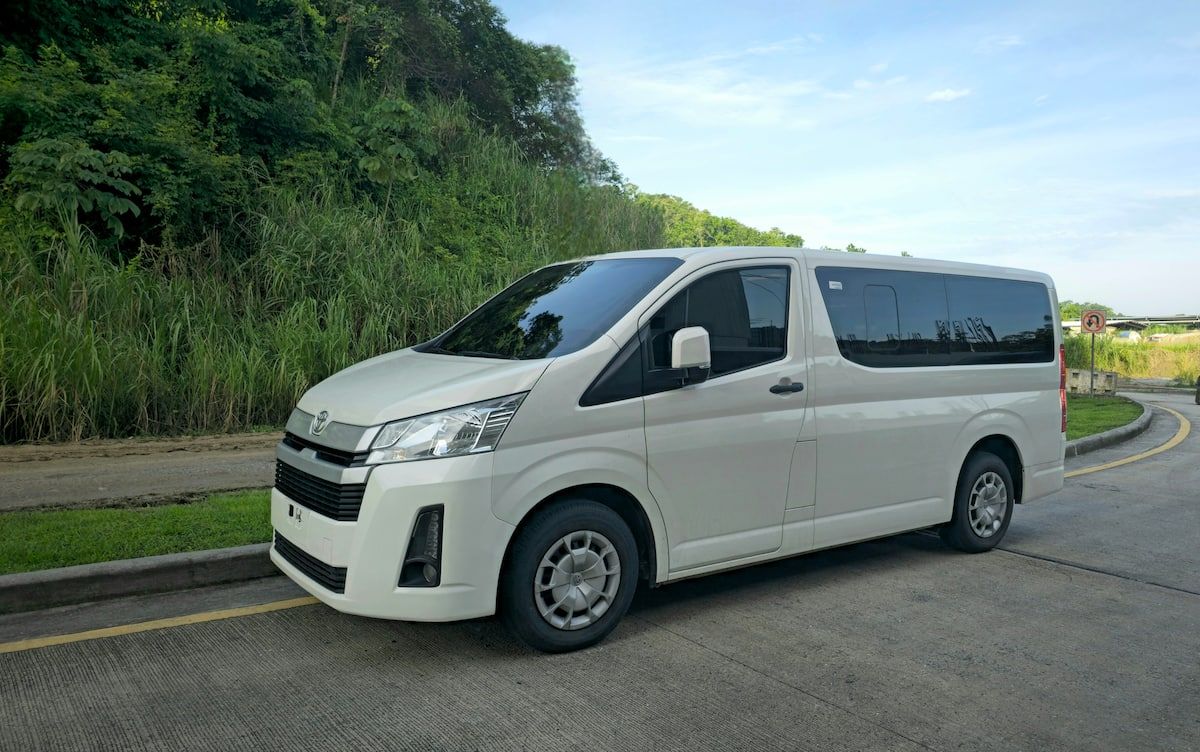 White Toyota Hiace minivan parked on a road surrounded by lush greenery, ready for a tour in Panama City, Panama.