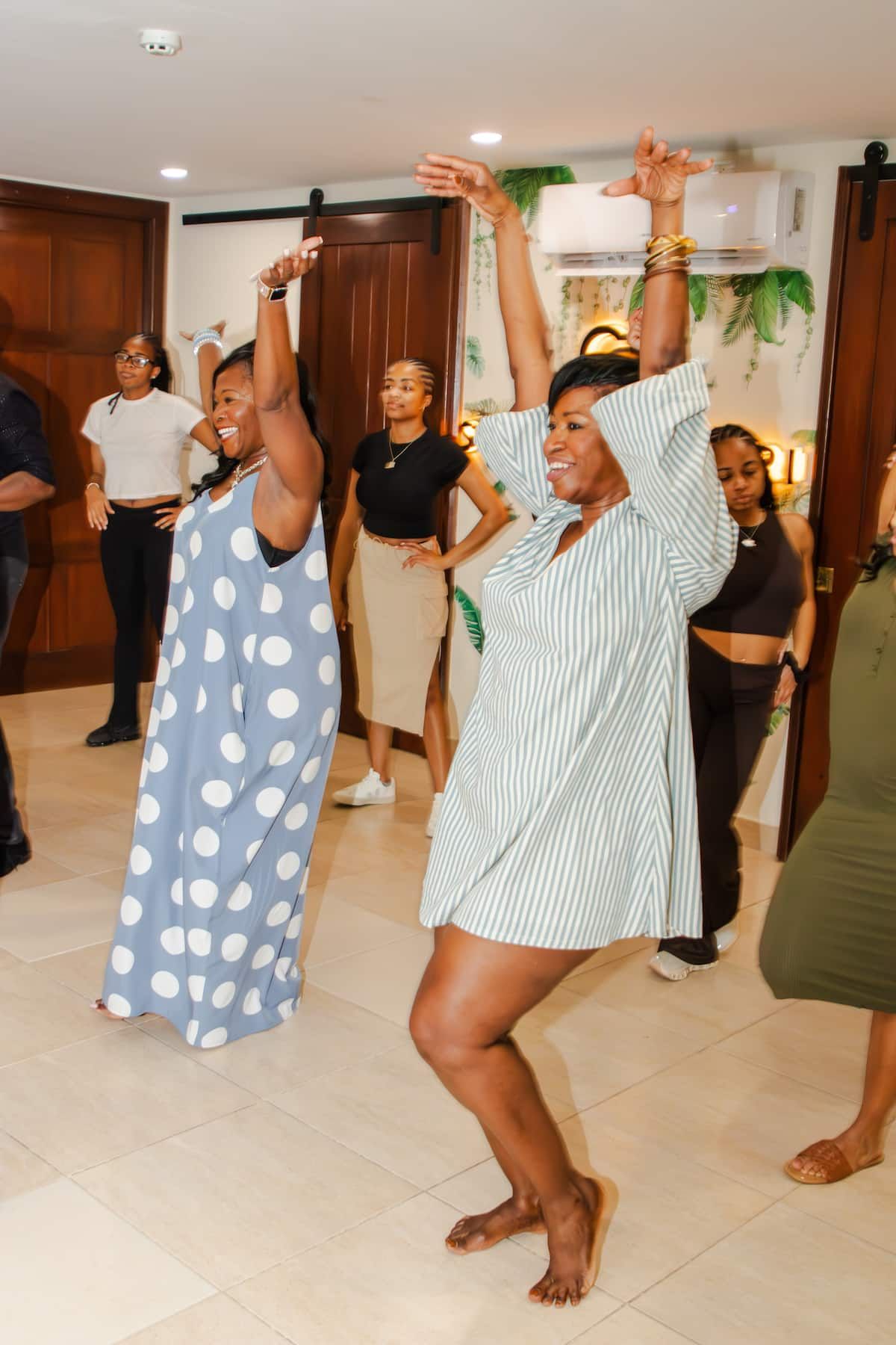 Two women dancing salsa in a lively indoor class at Bandits Adventure Tours Panama, surrounded by other participants in a tropical-themed room.