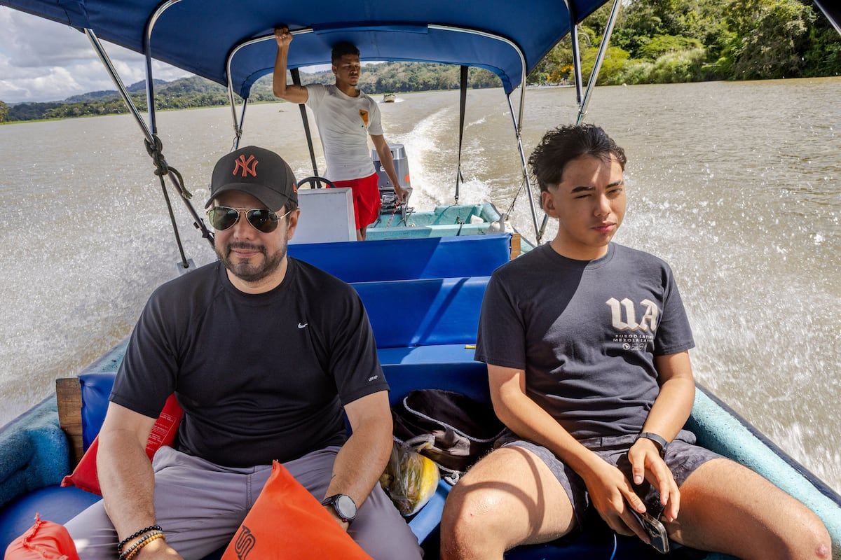 Three men enjoying a boat tour on Gatun Lake in Panama City, surrounded by lush greenery under a blue canopy.