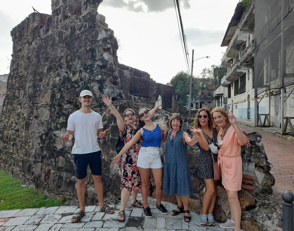 Group of tourists posing in front of an ancient stone wall during the Panama Canal Locks Casco Viejo Tour in Panama City, Panama.