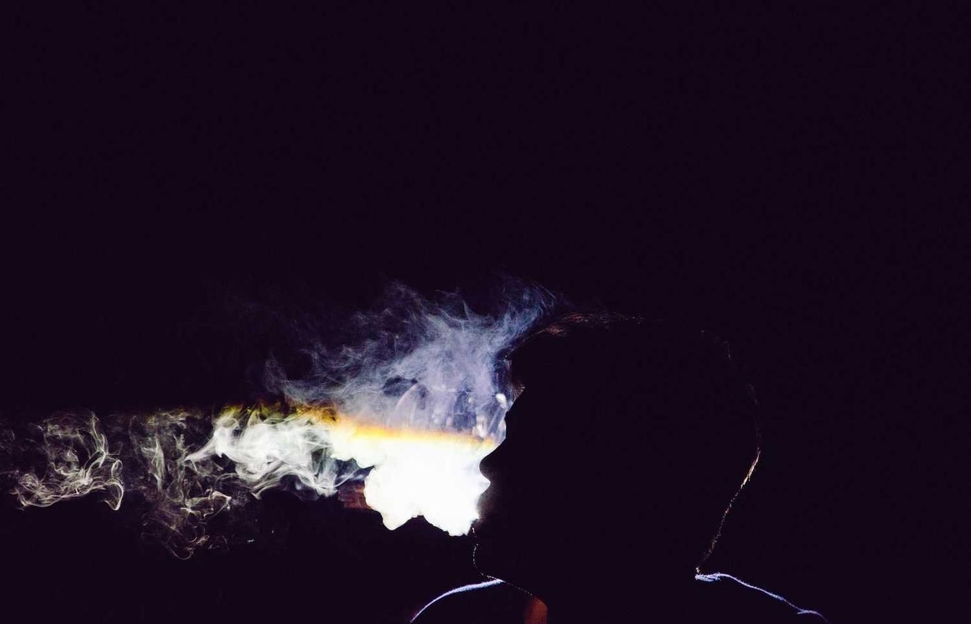 Silhouette of a person exhaling smoke in a dark setting, highlighting the mysterious ambiance of the Canal Locks Museum experience in Panama City.