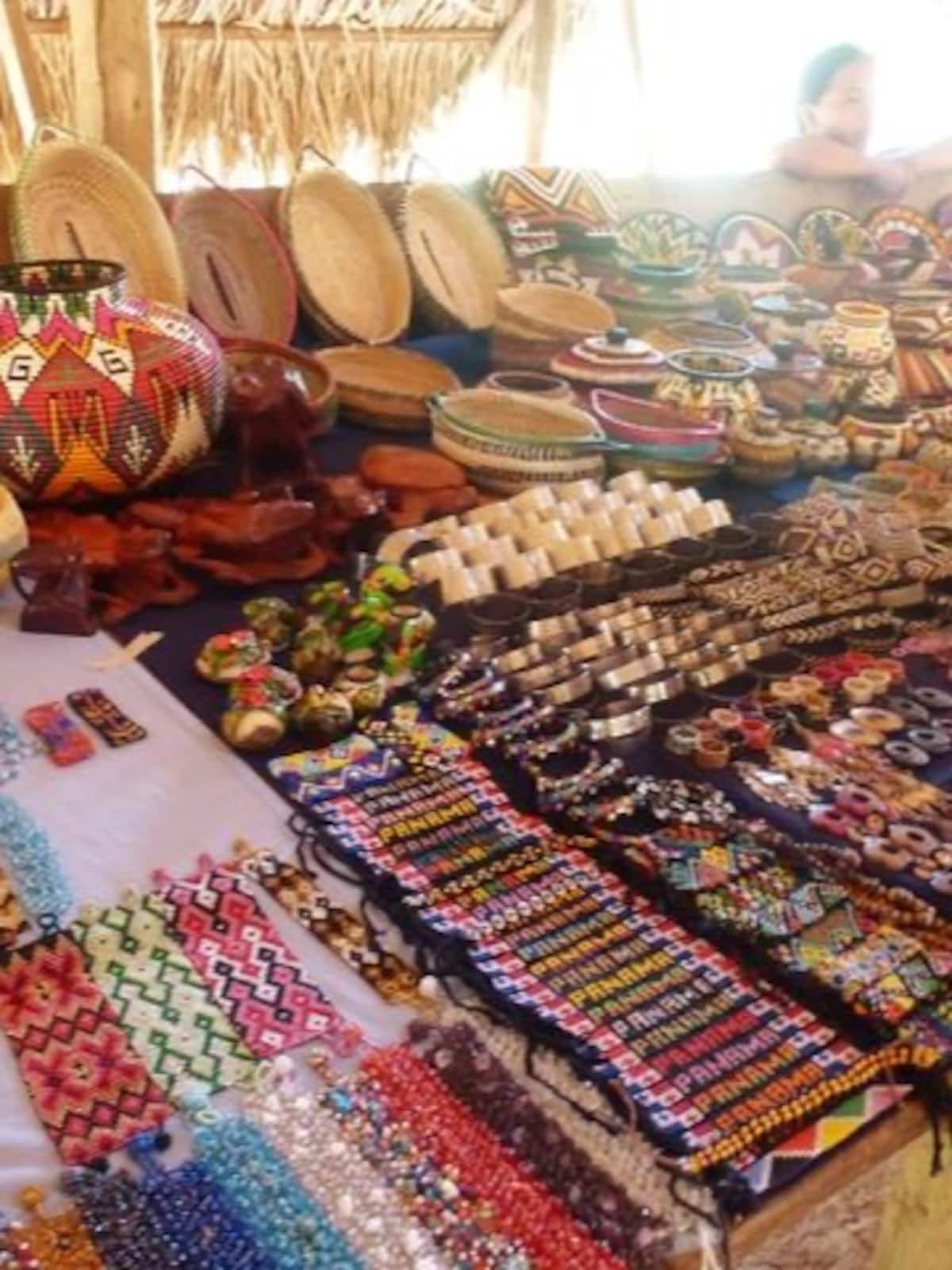 Vibrant display of traditional Panamanian handicrafts including woven baskets, beaded jewelry, and colorful textiles at an outdoor market stall.