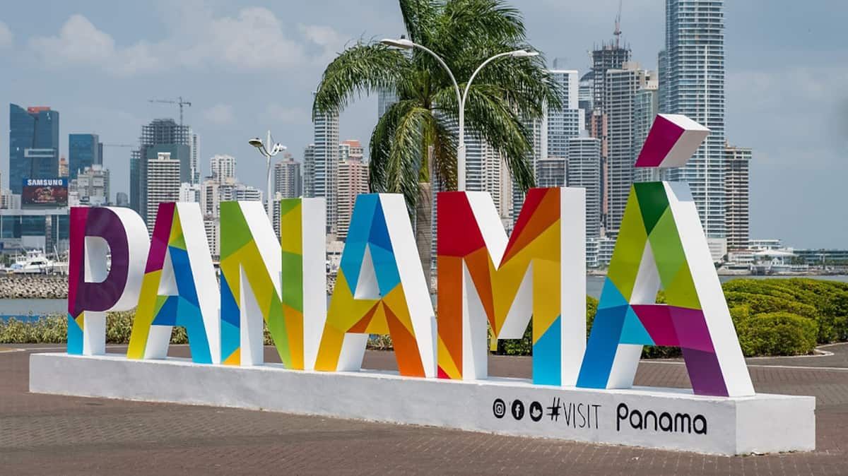 Vibrante letreiro 'PANAMÁ' em frente ao horizonte da Cidade do Panamá, promovendo uma experiência de tour pelo Canal do Panamá.