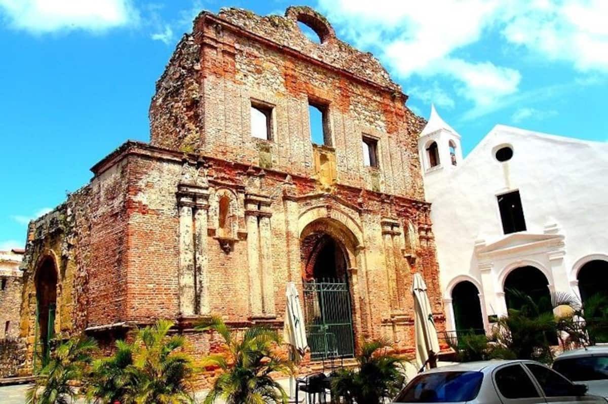 Ruined colonial church and white building in Panama City, showcasing historical architecture amidst tropical surroundings.