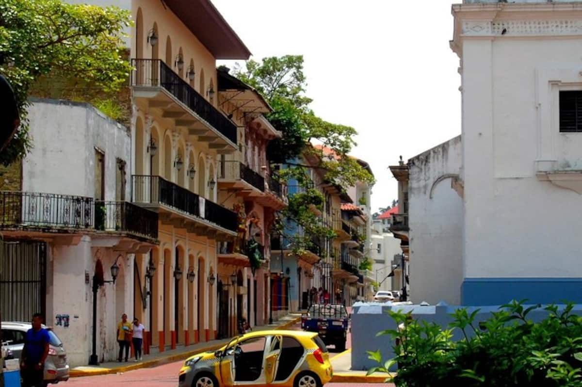 Vibrant colonial buildings and a yellow taxi on a sunny street in Panama City, Panama, showcasing the city's historic charm and lively atmosphere.