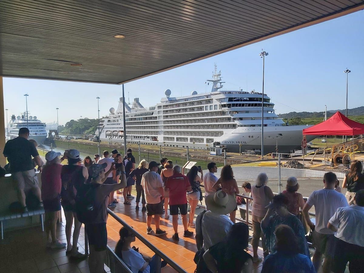 Des touristes observent un immense navire de croisière naviguant à travers le canal de Panama depuis le centre des visiteurs à Panama City, Panama.