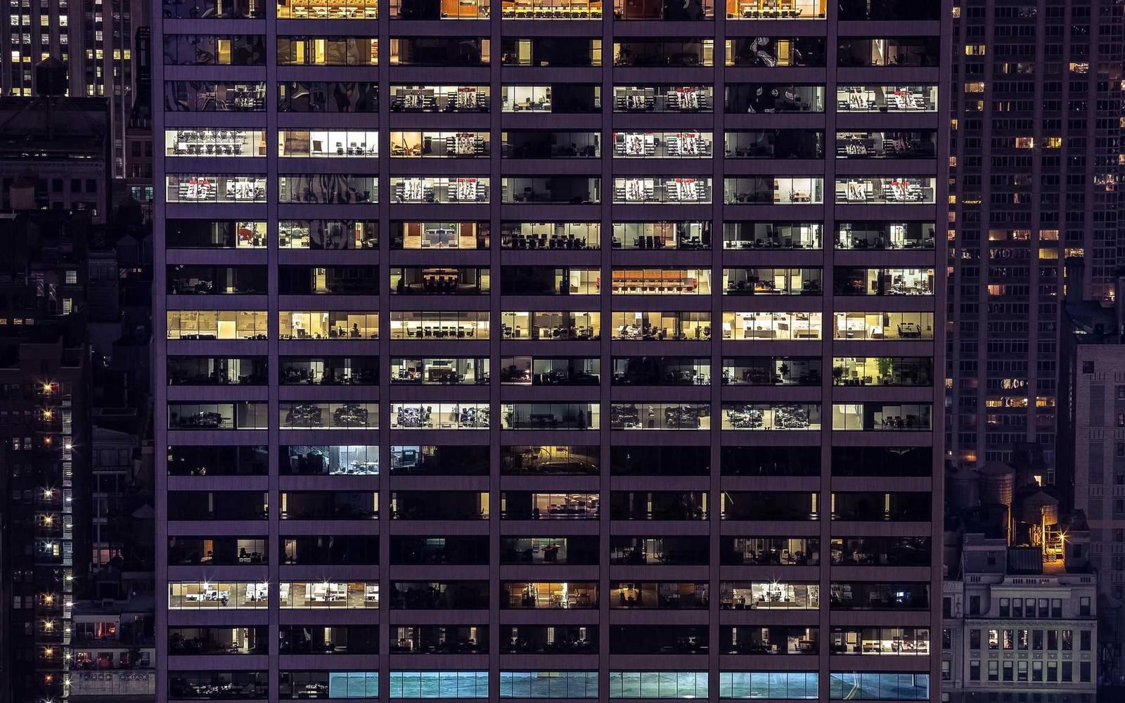 Aerial view of a high-rise office building in Panama City at night, showcasing illuminated windows and the urban skyline.