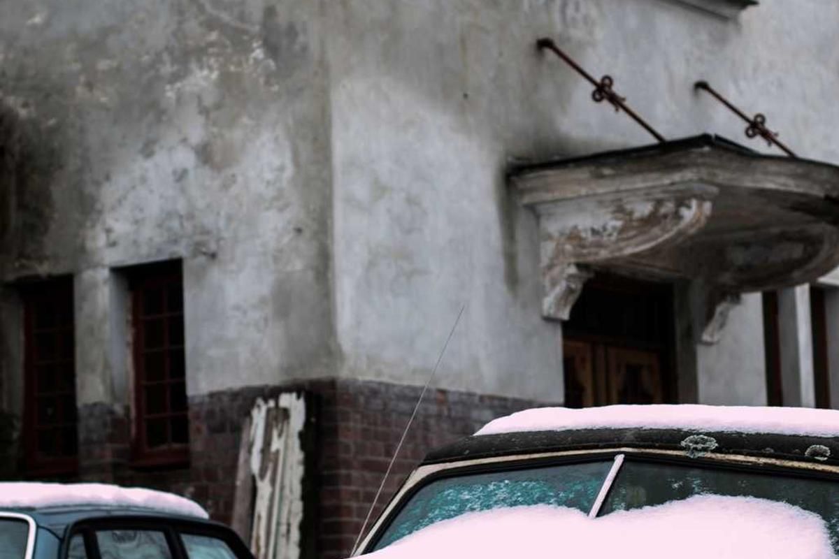 Snow-covered car parked in front of an old, weathered building with peeling paint and a rusty awning in Panama City, Panama