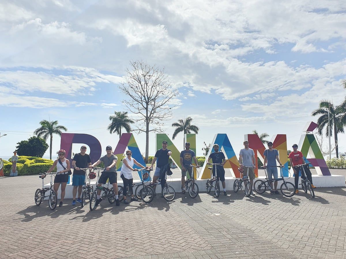 Group of cyclists posing in front of a colorful 'PANAMA' sign during a city bike tour in Panama City, Panama.