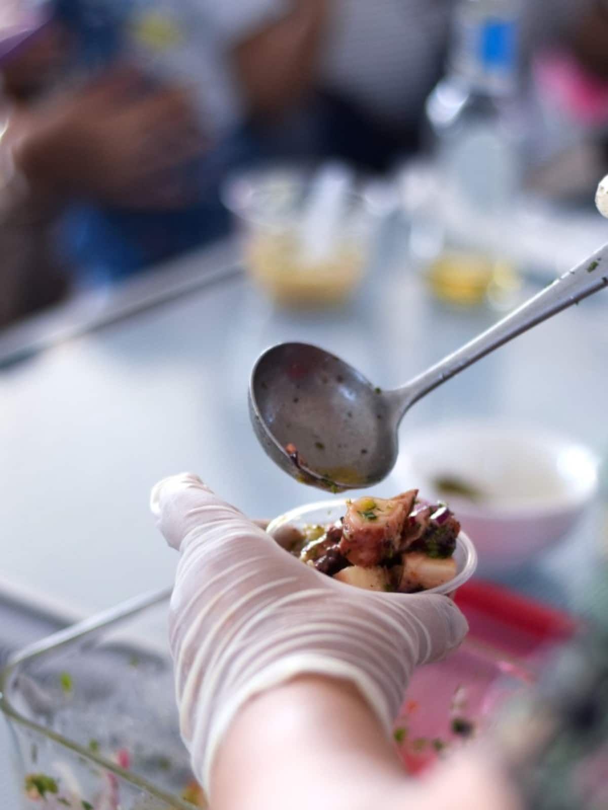 Gloved hand serving fresh ceviche with a spoon during a Panama City Markets Food Tour, showcasing local culinary delights.