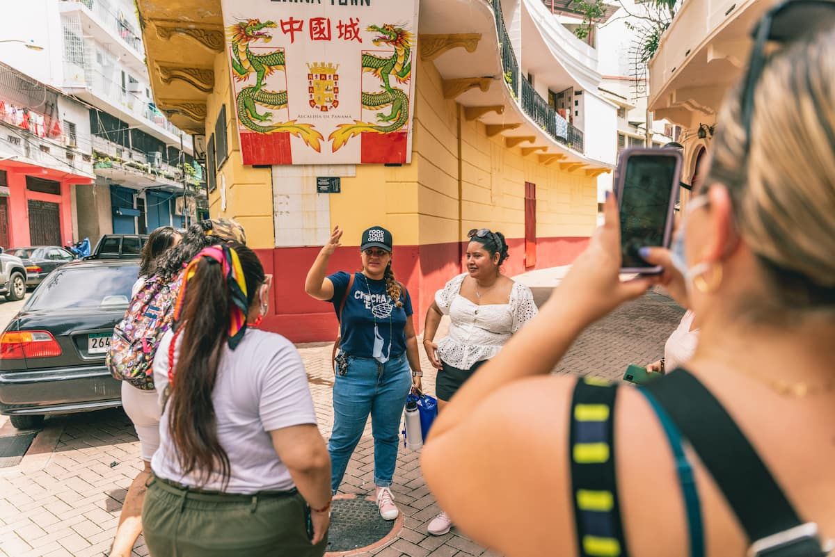 Tour guide leading a group of tourists through Panama City's Chinatown, capturing the vibrant culture and colorful street scene.