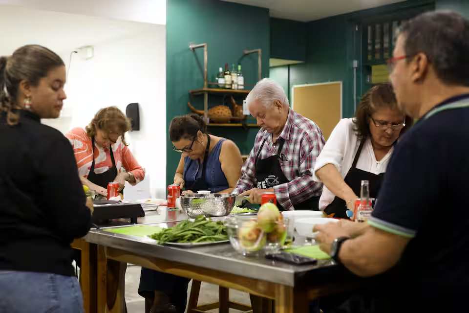 Participants in a Panama Cooking Class Traditional Recipes In Casco Viejo, wearing aprons and preparing food together in a modern kitchen setting.