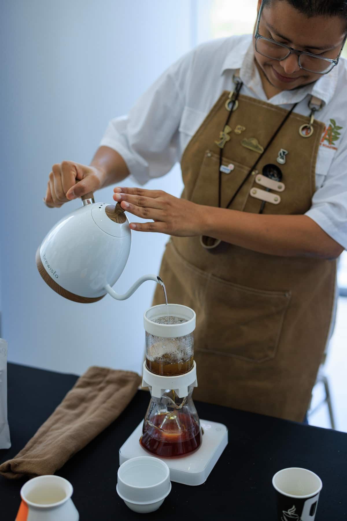 Barista pouring hot water into a coffee dripper during a Panama Geisha Specialty Coffee Tasting Experience in Panama City, showcasing the art of coffee brewing.