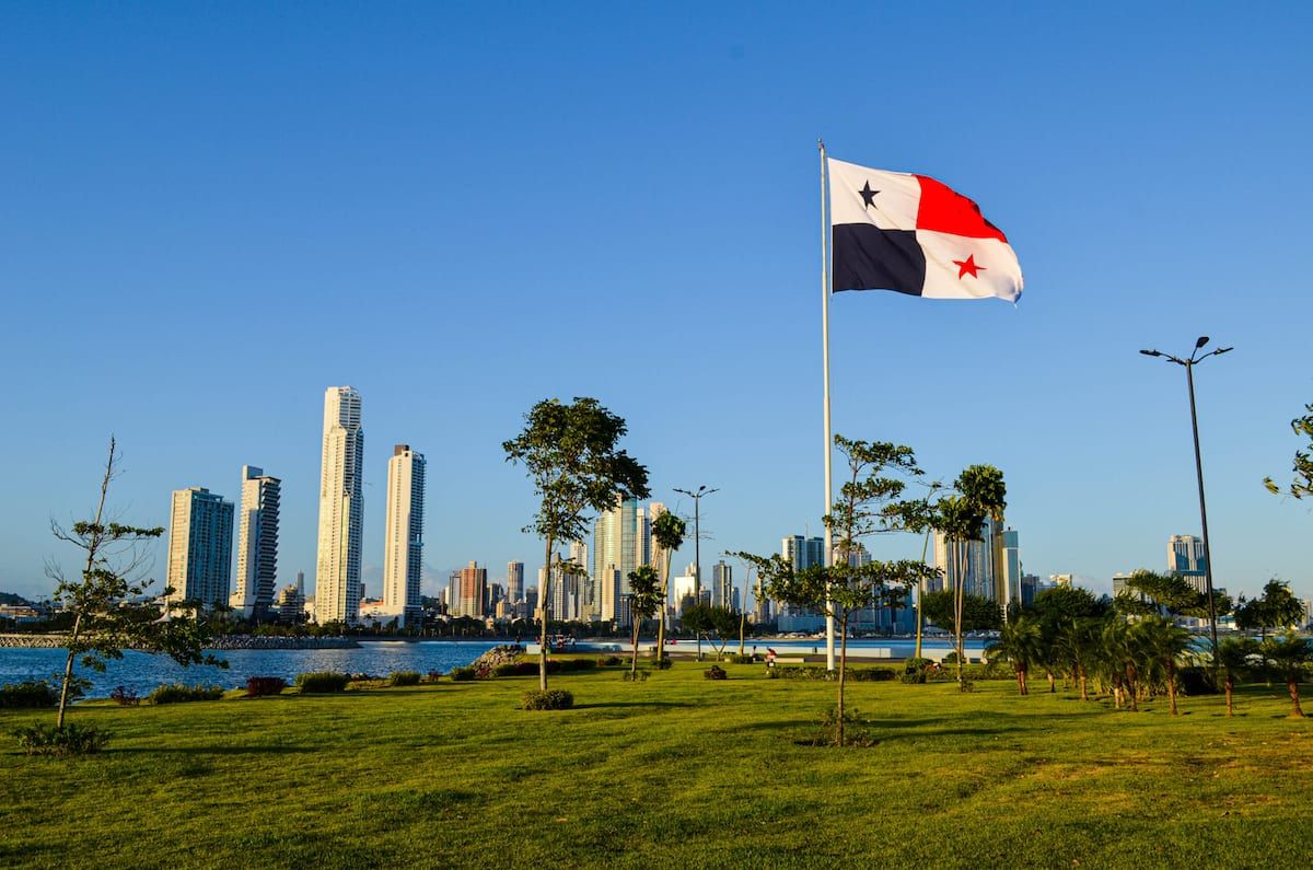 Panamanian flag waving in a green park with Panama City skyline in the background, showcasing a sunny day perfect for a social political walk.