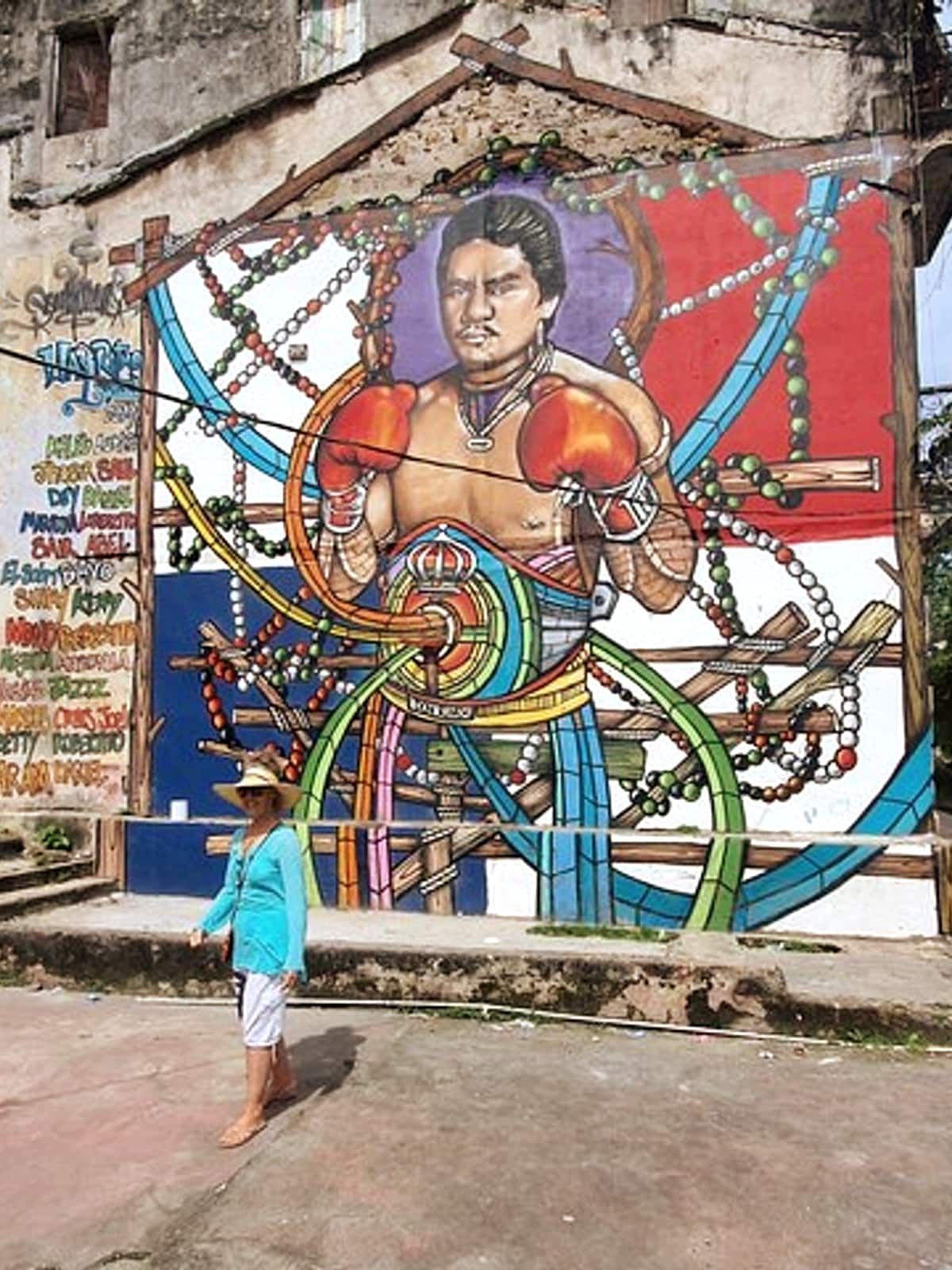 A woman walks past a colorful mural of a boxer in Panama City, showcasing the city's vibrant street art and cultural heritage.