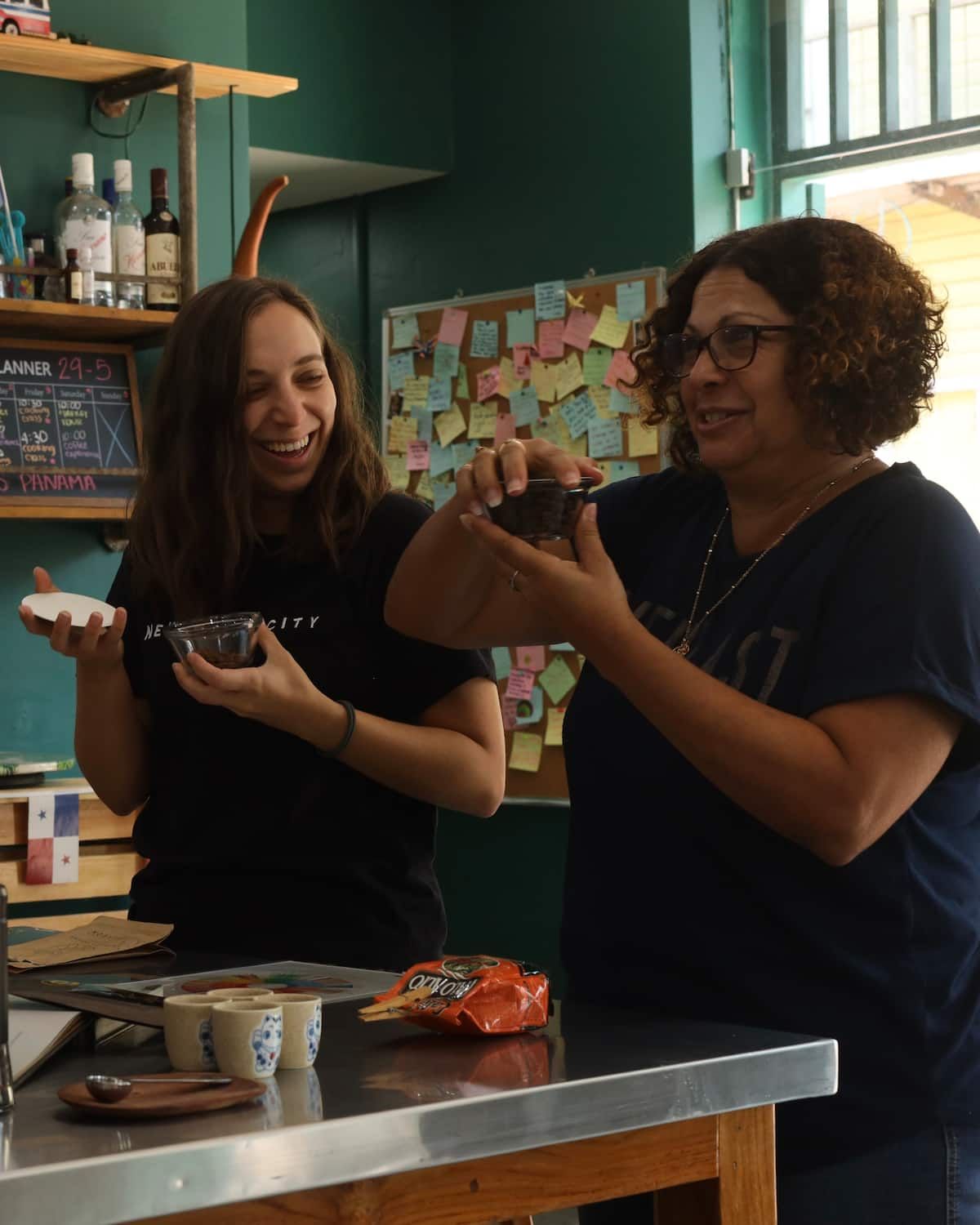 Two women laughing and tasting coffee beans during a Panamanian coffee tasting tour in Casco Viejo, Panama City.