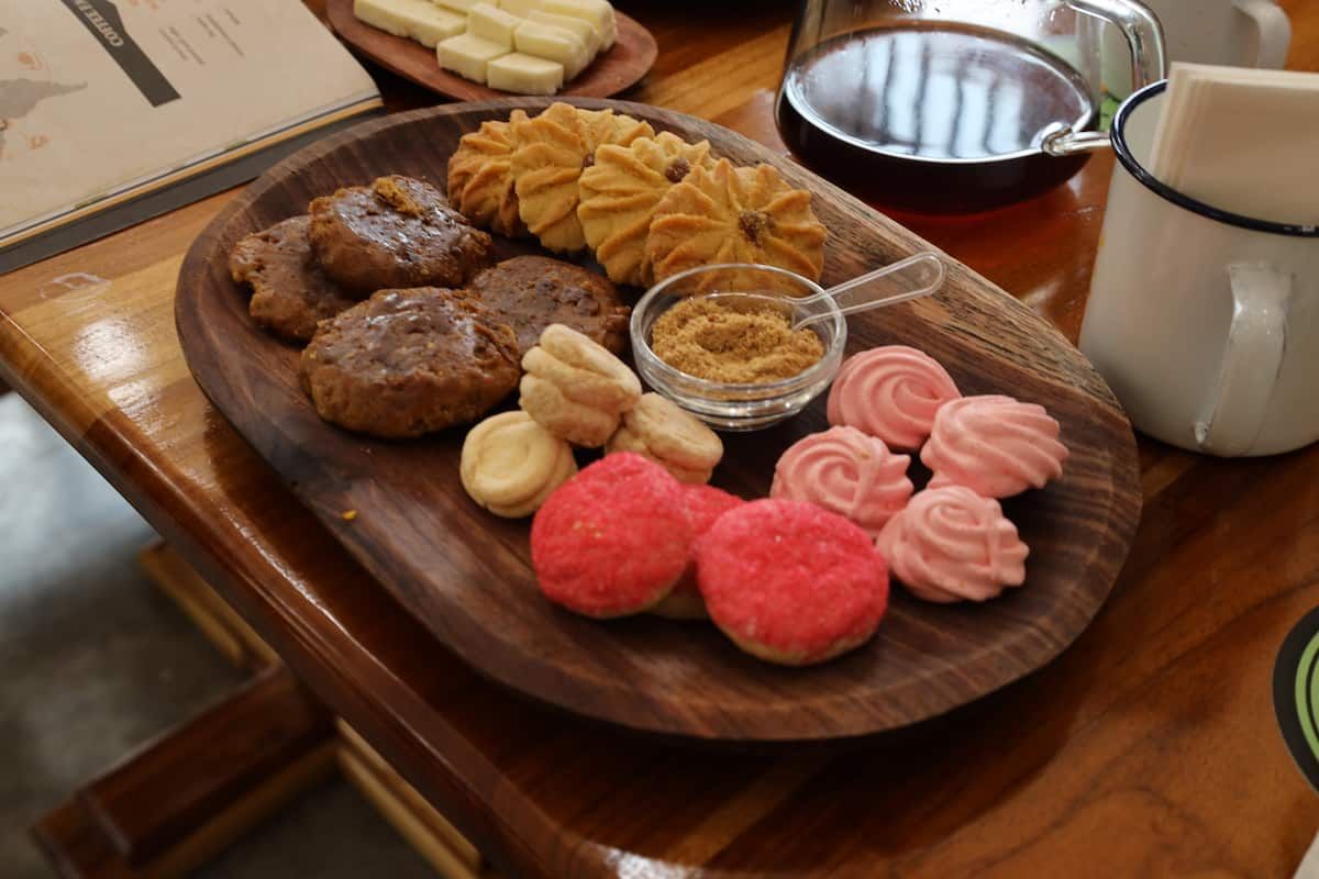 Assorted cookies and pastries served on a wooden tray, accompanied by sugar and a coffee mug, at a café in Panama City.