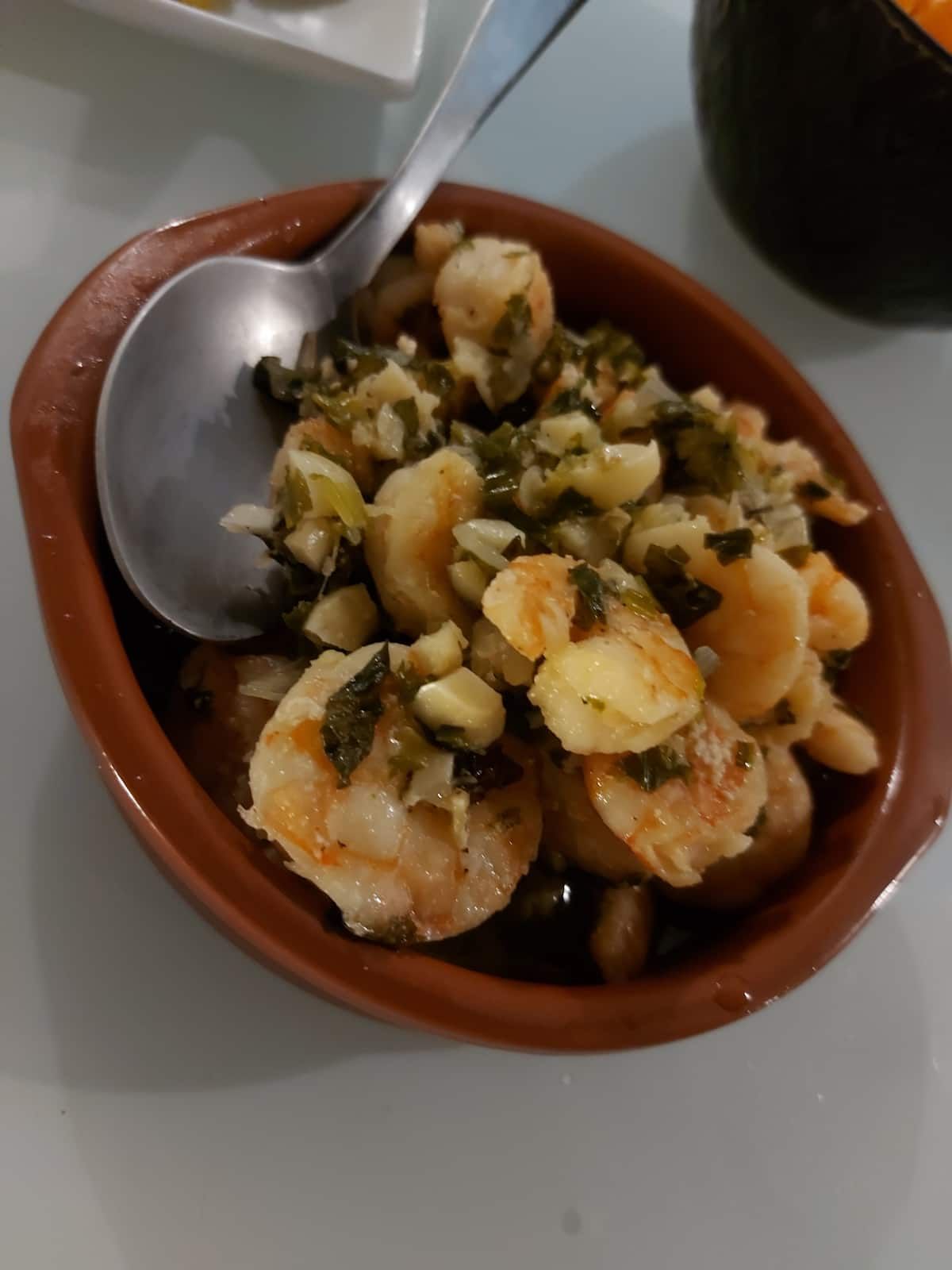 Traditional Panamanian shrimp dish garnished with garlic and herbs, served in a rustic terracotta bowl during a cooking class in Casco Viejo, Panama City.