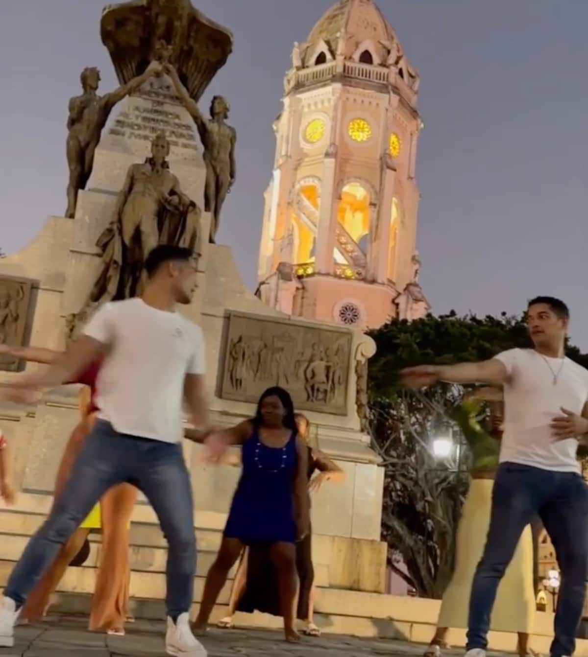 Salsa dancers performing in front of a historic monument and clock tower in Casco Viejo, Panama City during an evening tour.