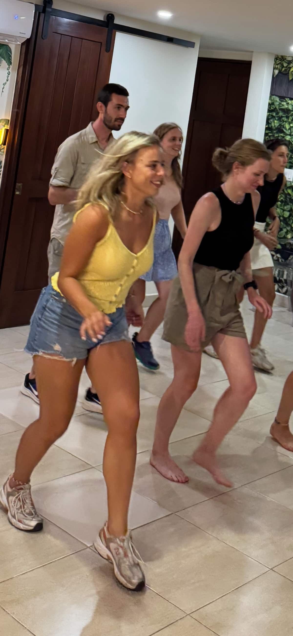 Group of people dancing salsa in an indoor setting, led by a woman in a yellow top, as part of a custom choreography experience in Panama City.