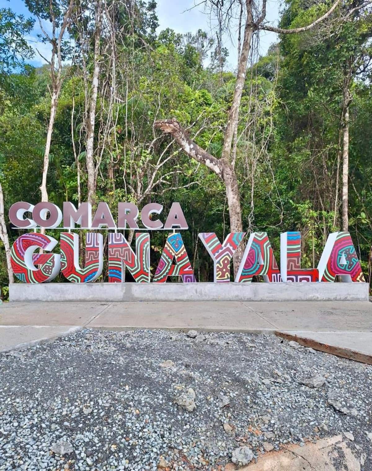 Vibrant 'Comarca Gunayala' sign with colorful patterns set against a lush tropical forest backdrop, highlighting the cultural and natural beauty of Panama's San Blas Islands.