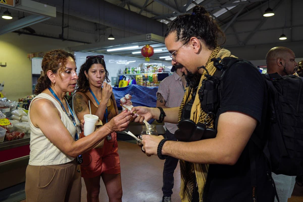 Tour guide offering street food samples to participants at a market in Panama City during a Bandits Adventure Tours experience.