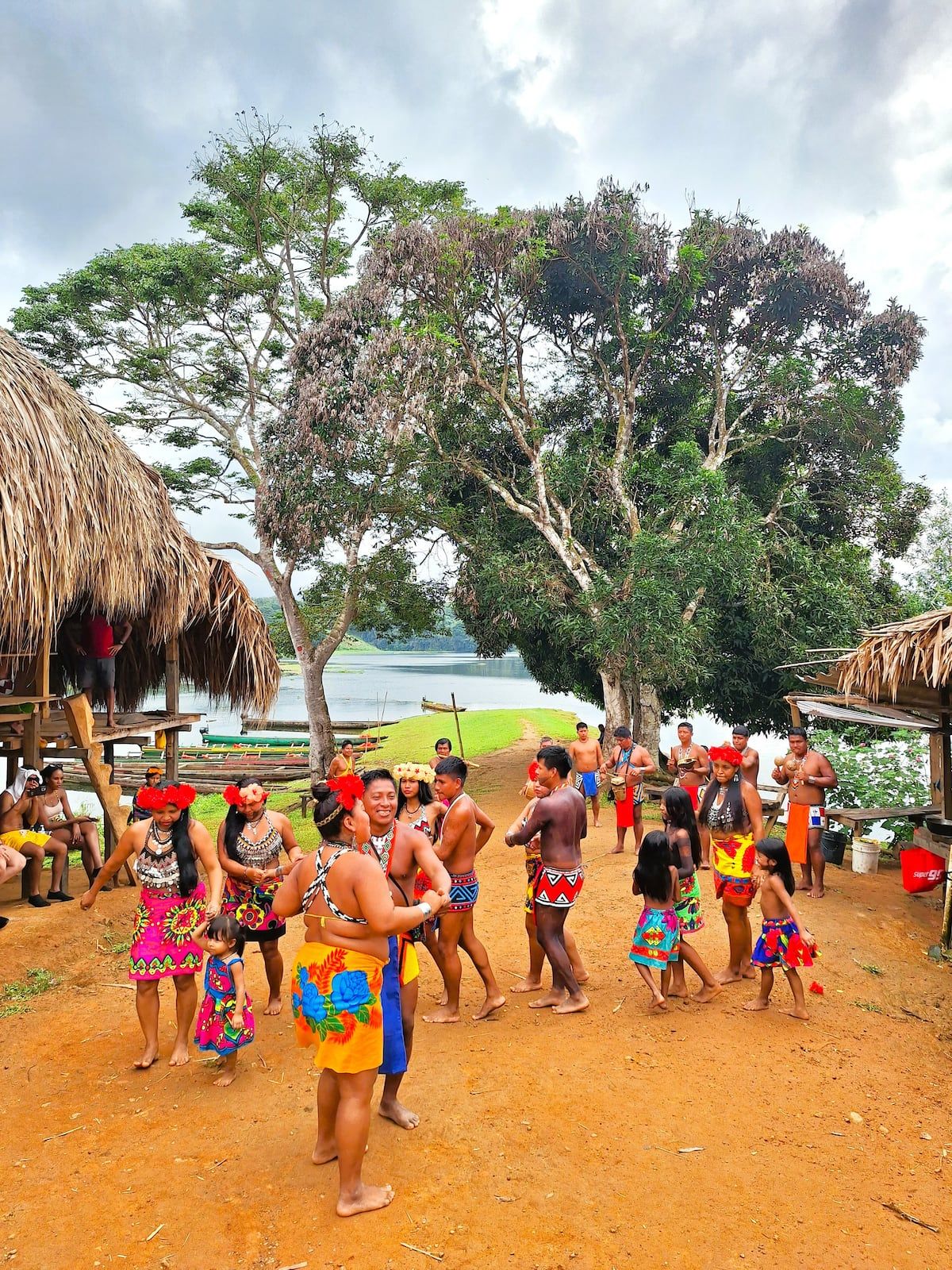 Embera people in vibrant traditional clothing dancing in their village near a river, showcasing cultural heritage during a tour in Panama City.